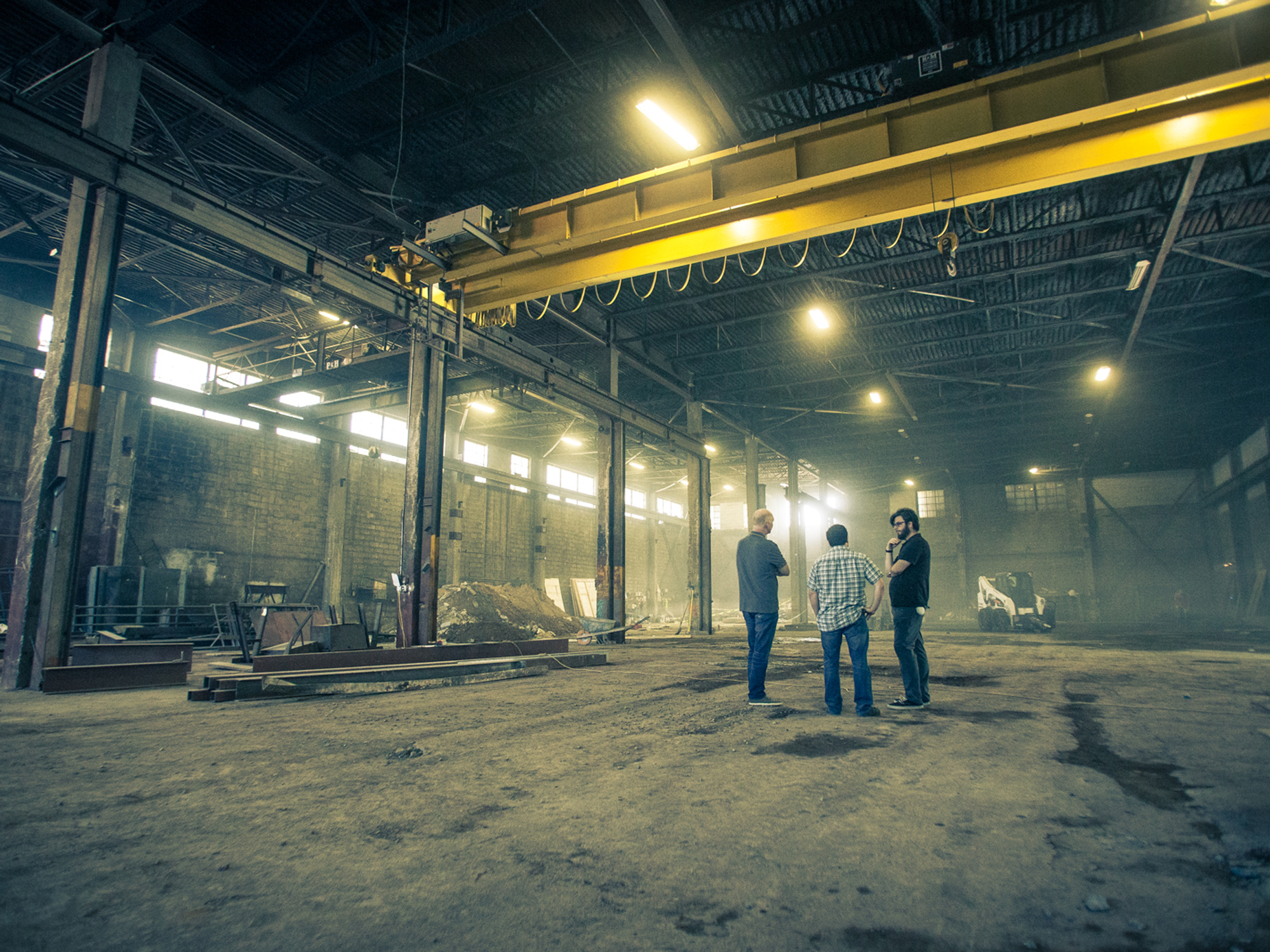 Interior view of an industrial space in the midst of construction with a group of people discussing plans.