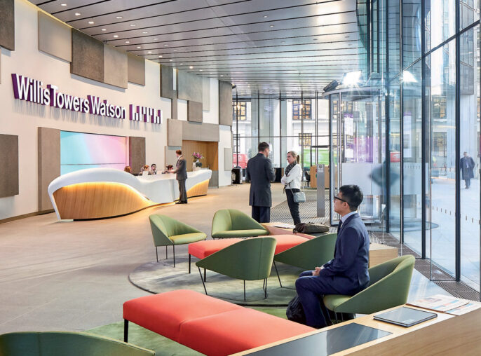Modern corporate lobby featuring a curved reception desk, sleek glass walls, and an array of colorful seating options set on a polished concrete floor, accentuated by natural light and digital display screens.