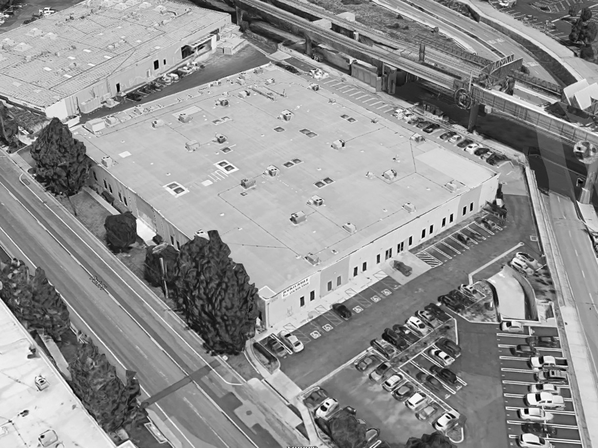Aerial view of a former warehouse building with an adjacent parking lot.