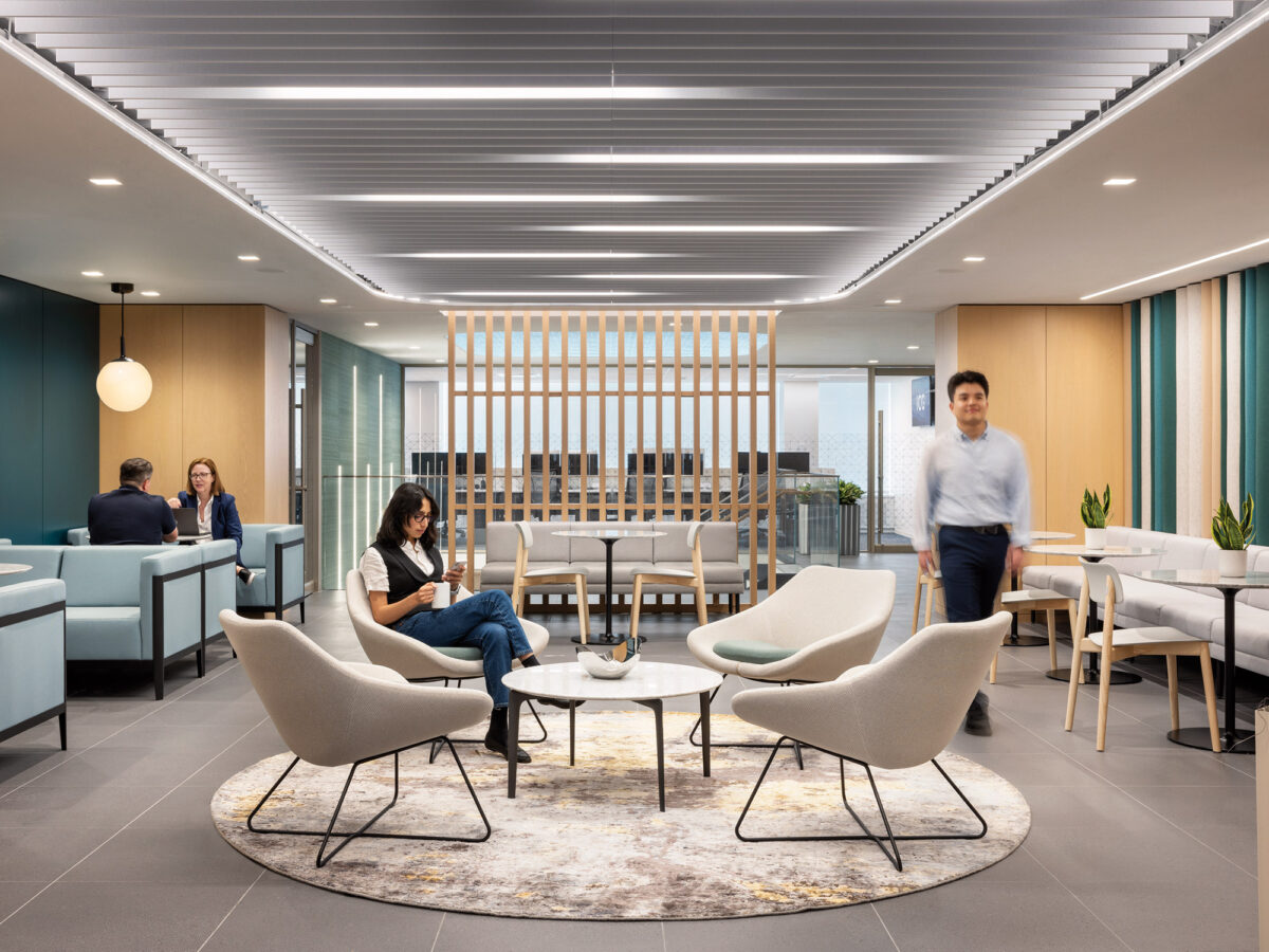 A modern office space featuring a blend of sleek architectural design with natural elements, incorporating a striking staircase, lush indoor plants, and a designated hub area for work and collaboration.