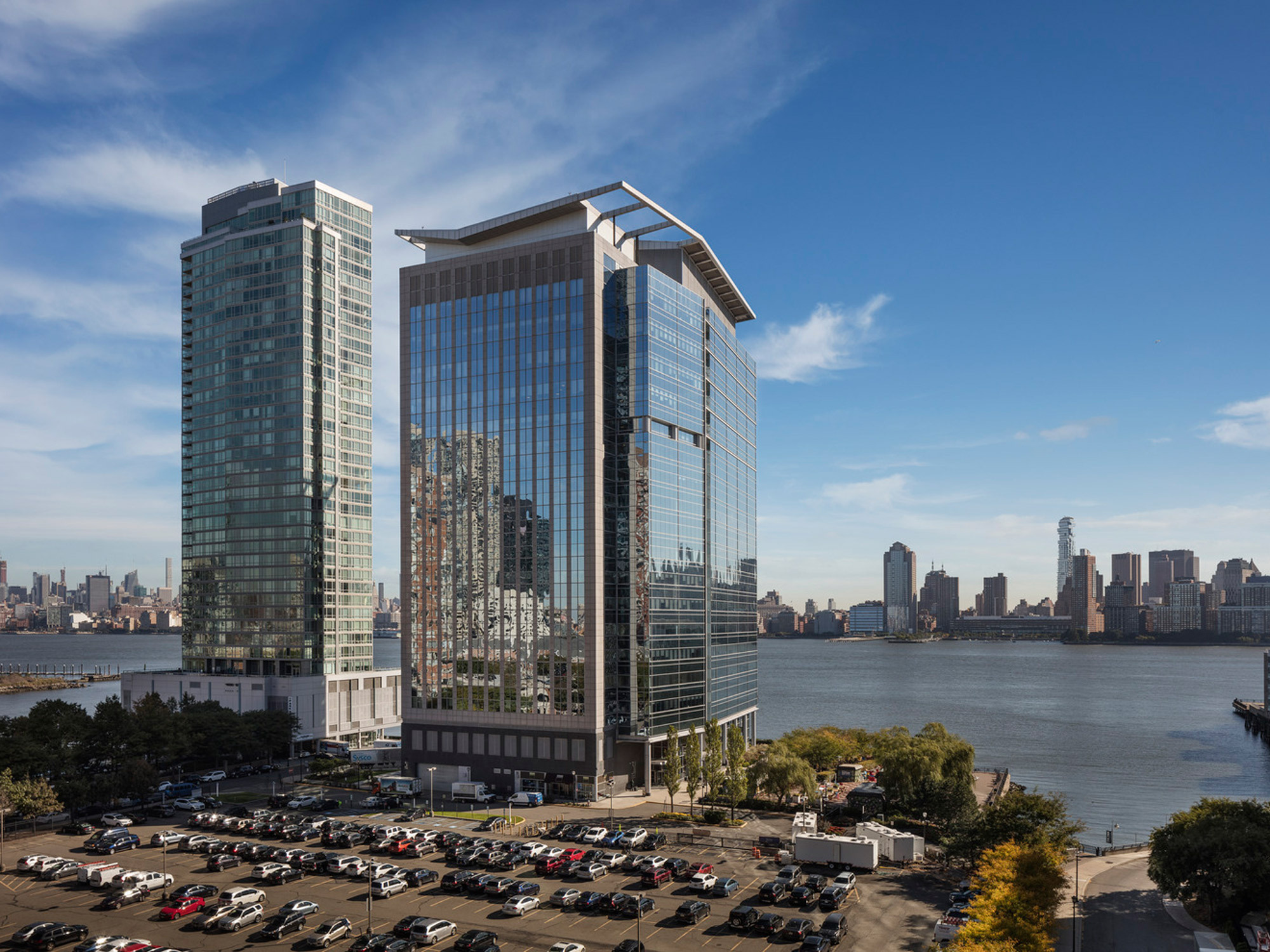 Modern waterfront skyscrapers with reflective glass facades, showcasing a blend of residential and commercial architecture against a clear blue sky.