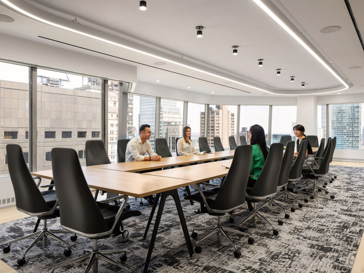 Modern conference room boasting an elongated wooden table surrounded by black ergonomic chairs, complemented by a patterned gray carpet. Curved overhead LED lighting echoes the room's sleek lines, while floor-to-ceiling windows offer an urban skyline view.