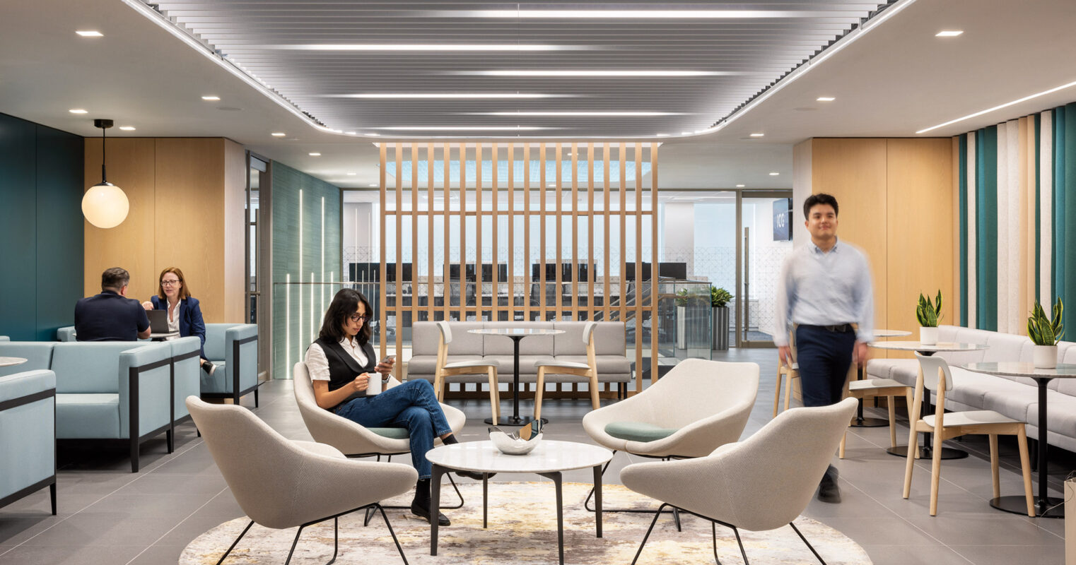 A modern office space featuring a blend of sleek architectural design with natural elements, incorporating a striking staircase, lush indoor plants, and a designated hub area for work and collaboration.