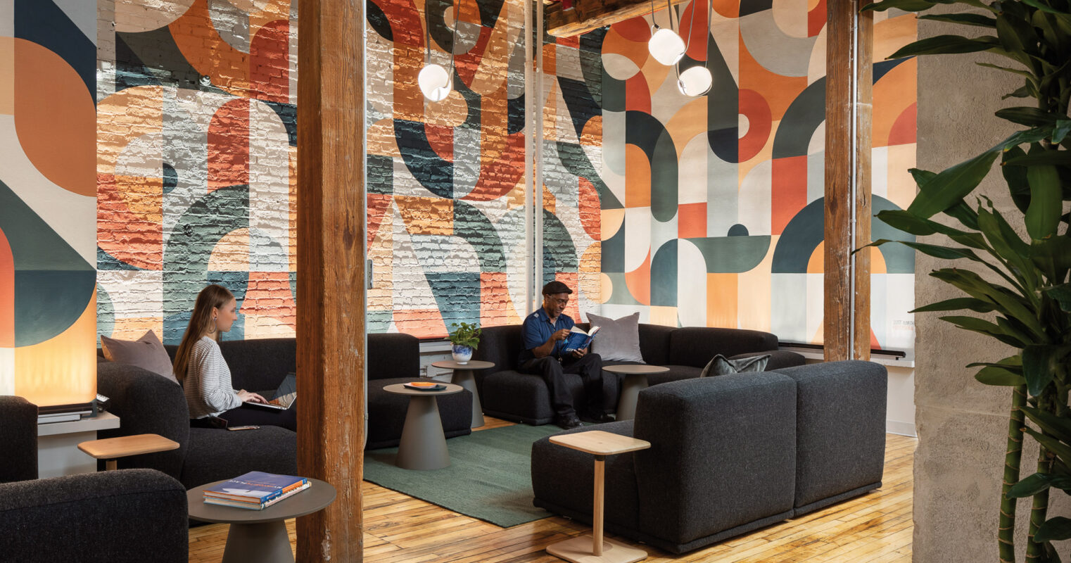 A modern, office environment with a vibrant and colorful painted wall design. The office features high ceilings and contemporary lighting fixtures