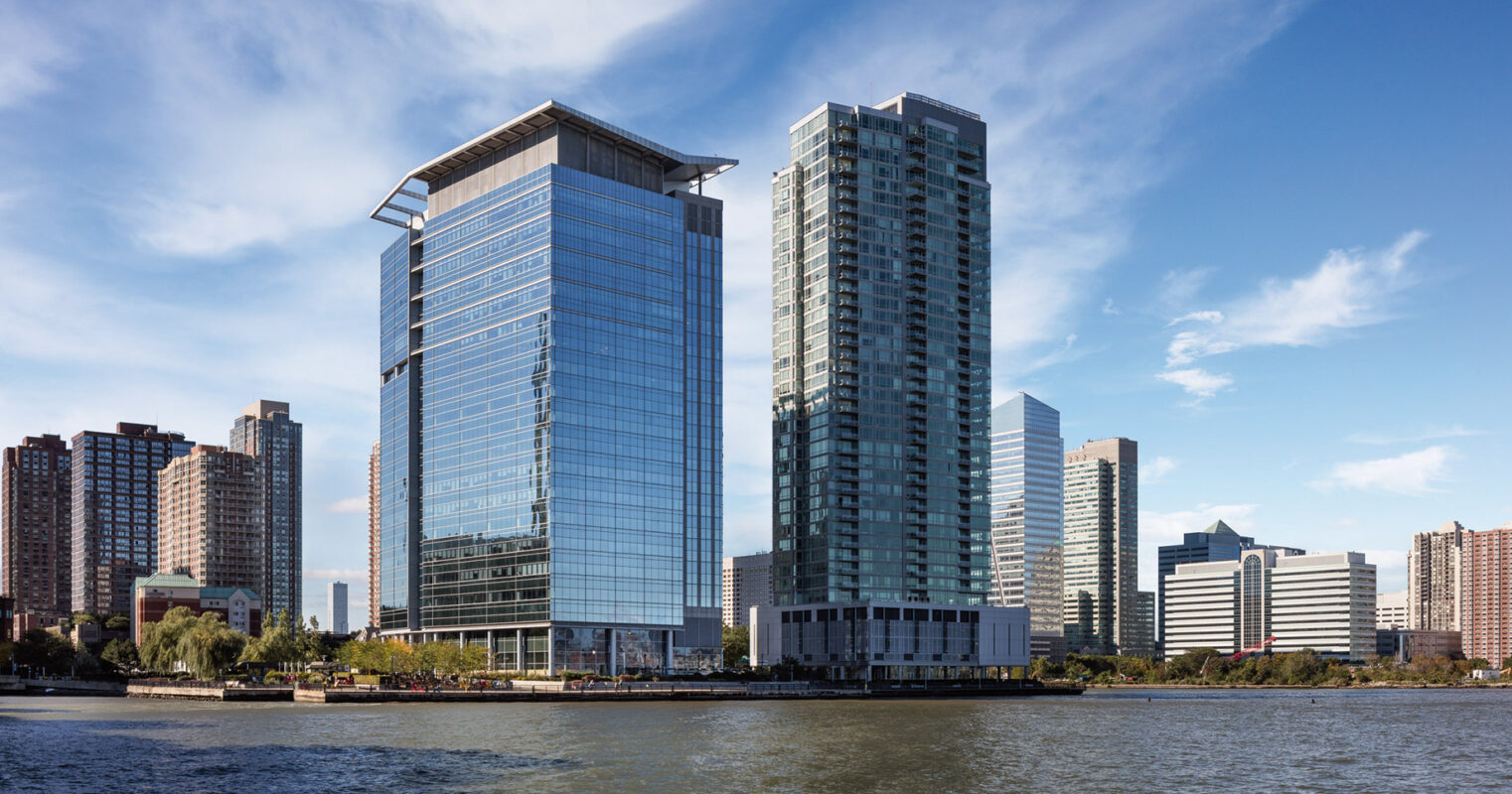 Modern skyscrapers by the waterfront against a clear blue sky, exemplifying contemporary urban architecture.
