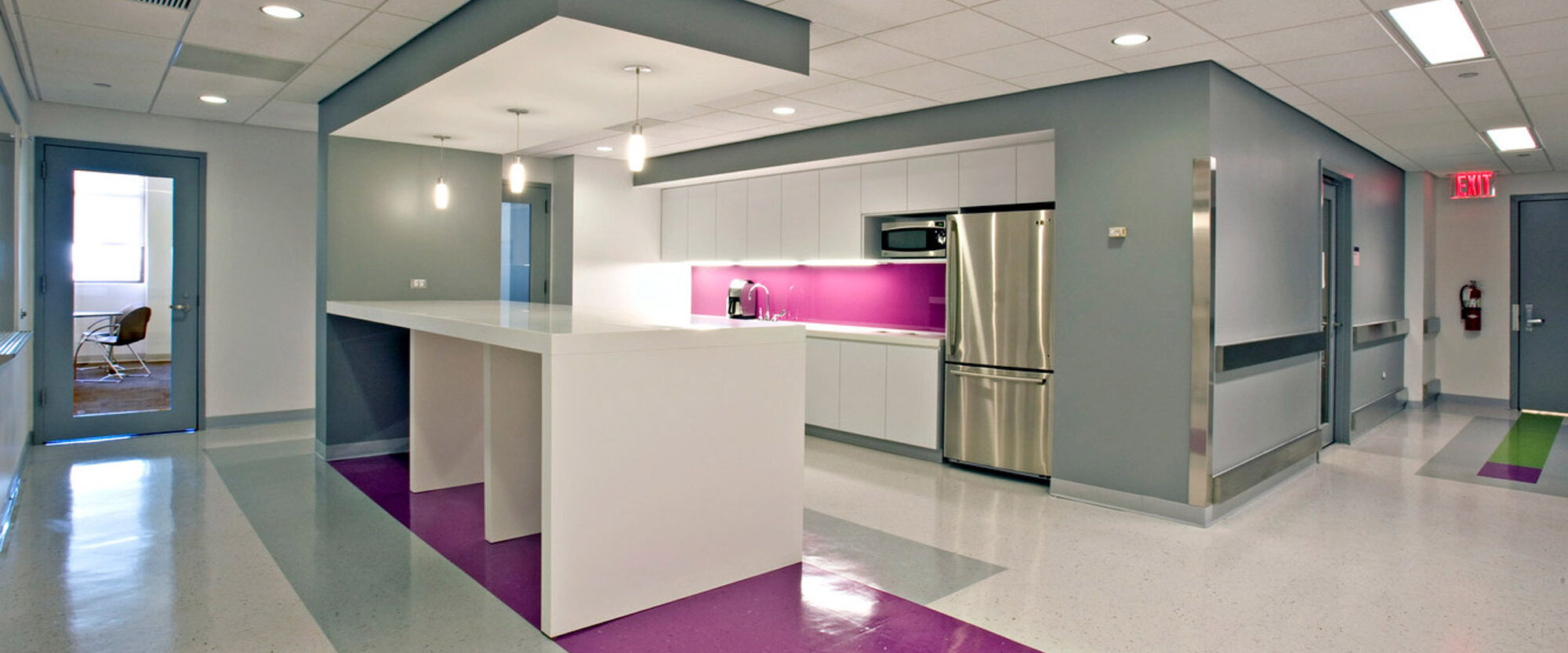 Modern interior with geometric design elements, featuring a neutral palette with pops of green and purple on the flooring. Clean lines and well-lit spaces emphasize functionality and contemporary style.