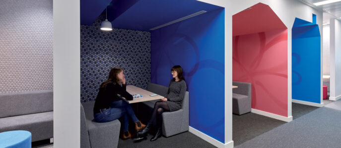 Modern office breakout area featuring house-shaped alcoves with vibrant blue accents, acoustical wall treatments, and integrated seating for casual meetings.