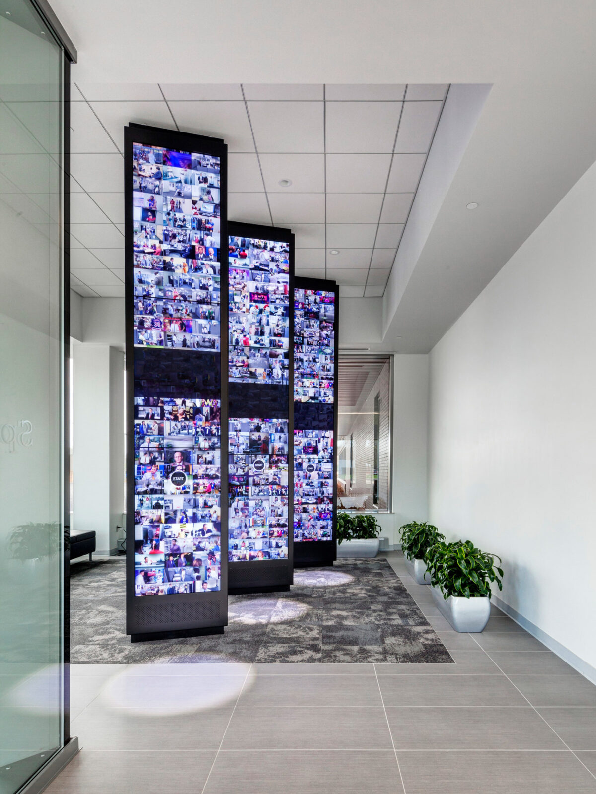 Modern office interior featuring an interactive media wall composed of multiple digital screens displaying dynamic content, contrasted with minimalist decor and neutral tones.