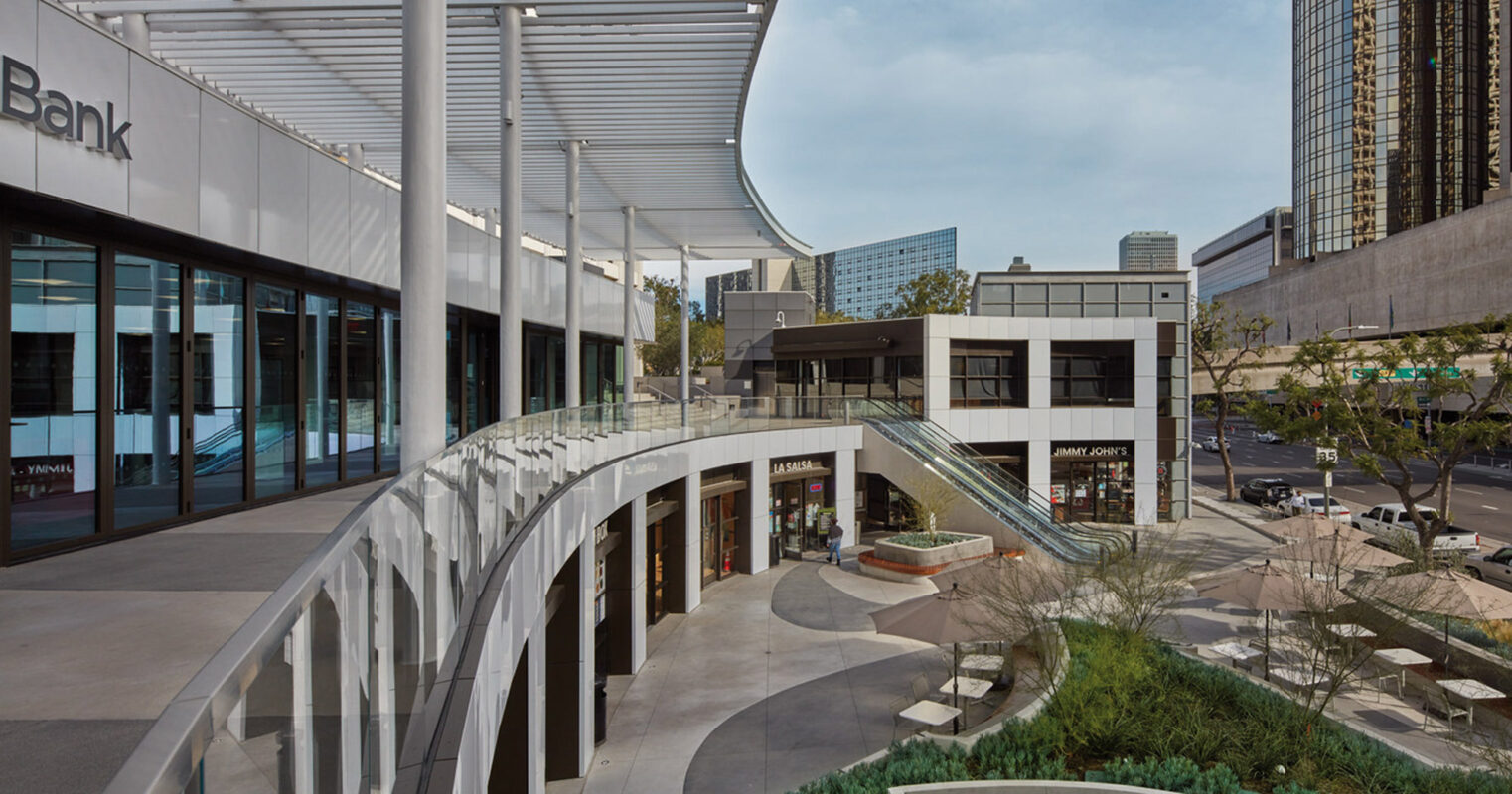 Modern urban plaza featuring curvilinear walkways, streamlined metal pergolas, lush landscaping, and multi-level commercial spaces under a clear sky, illustrating thoughtful integration of open-air design and contemporary architecture.