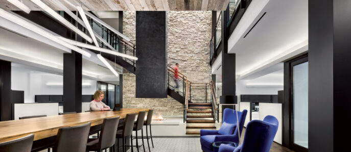 Modern interior design featuring a contrast of textures with exposed wooden beams, stone accent walls, and a geometric tiled floor. Sleek black metal staircases connect multi-level spaces, while royal blue armchairs add a pop of color to the predominantly neutral palette.
