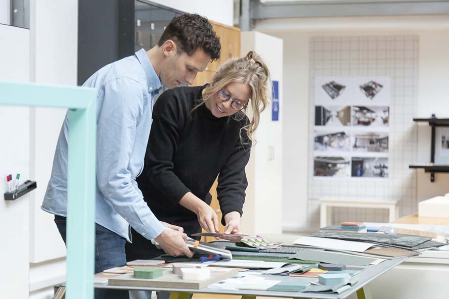 Two designers in an office viewing material swatches.